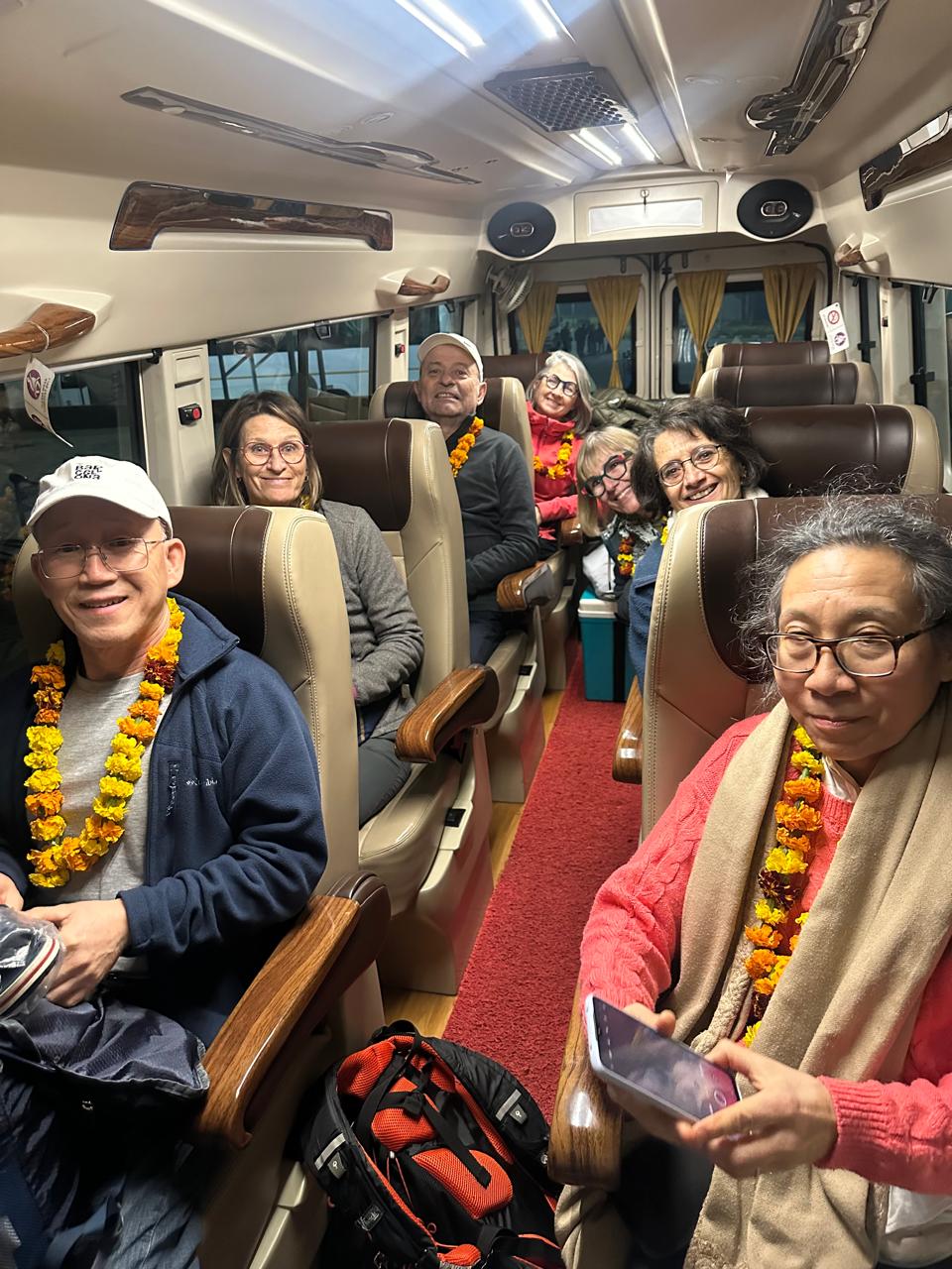 A group wearing marigold garlands aboard a tempo traveller minibus in India