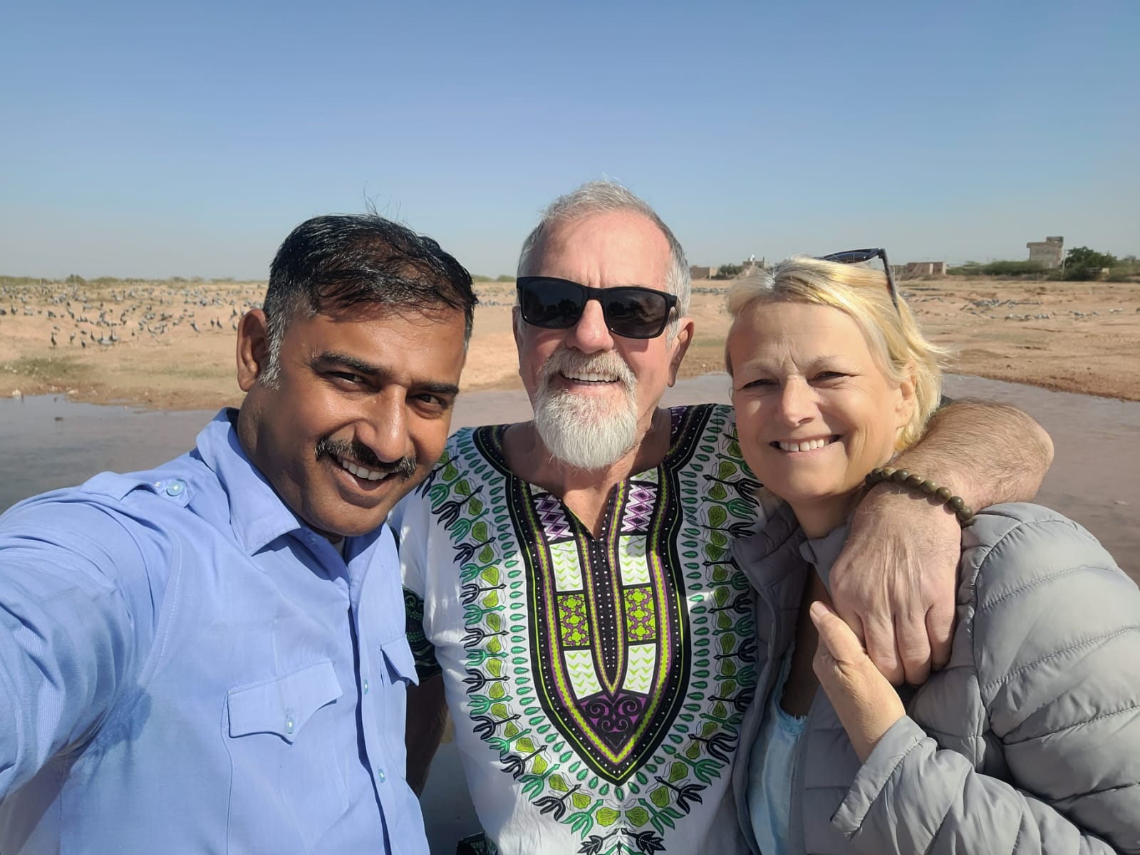 A couple and their driver at a desert lake with migrating cranes, Rajasthan
