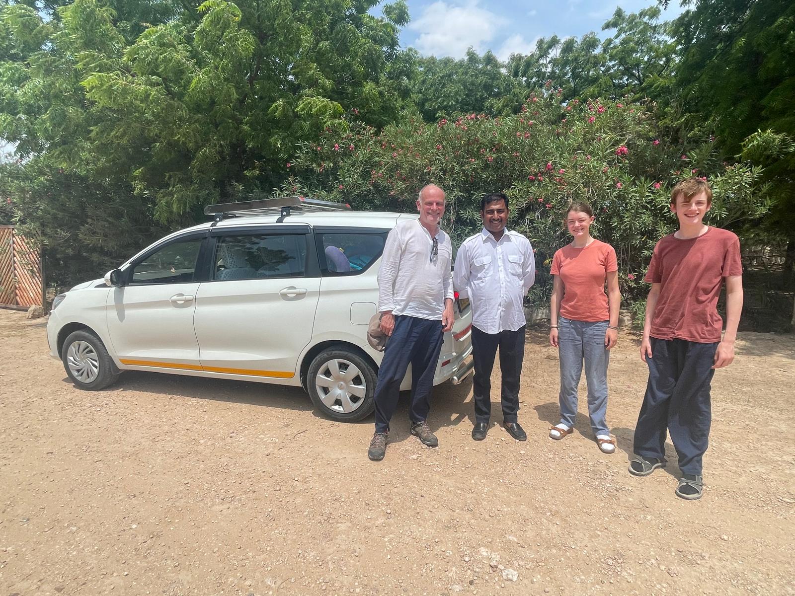 A family with their driver beside the car on a Rajasthan road trip