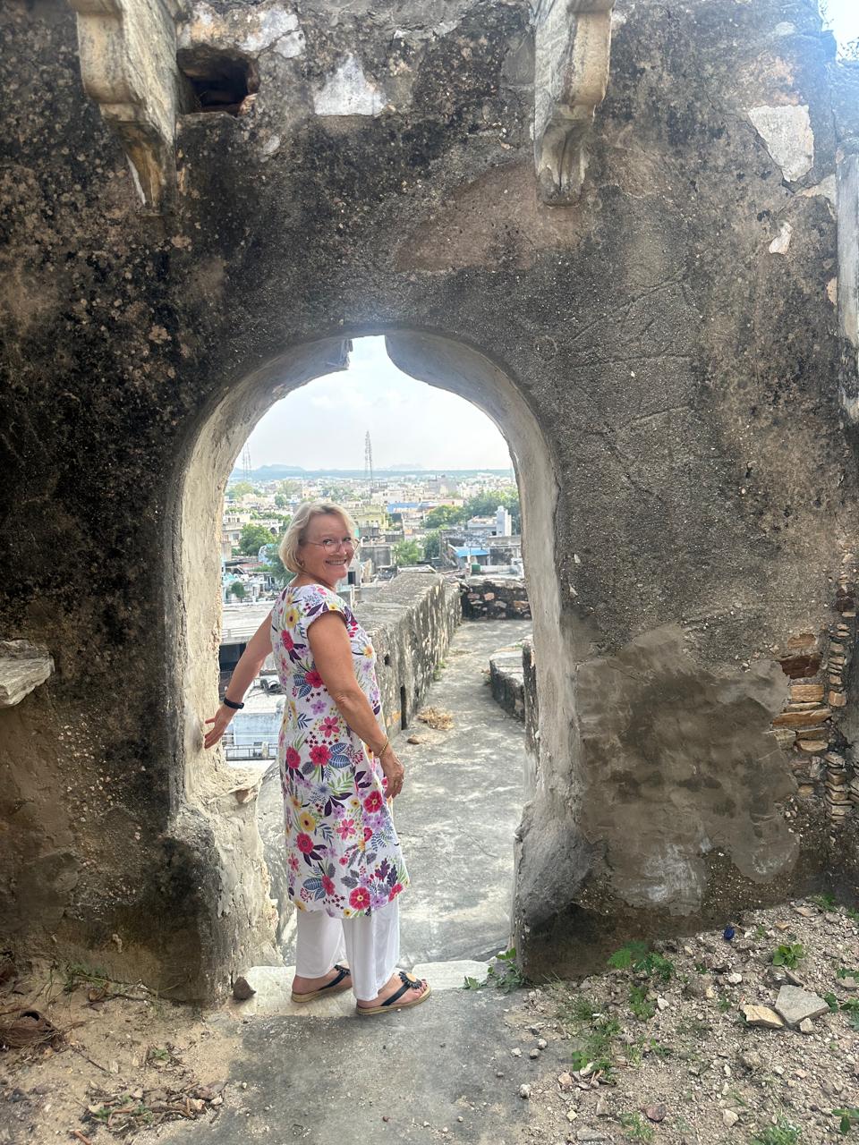 A guest framed in an old fort archway above a Rajasthan town